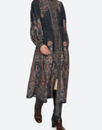 Woman wearing a long, patterned dress on a white background