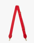 Red bag strap with gold hardware on a white background