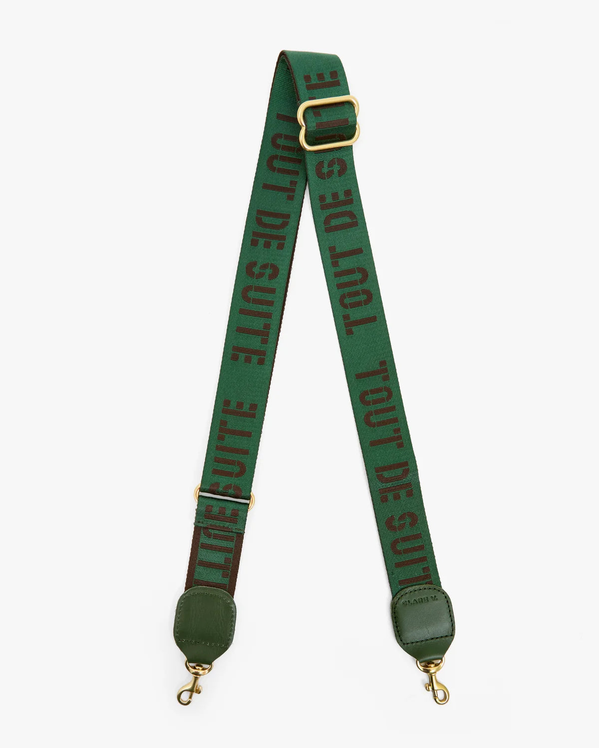 A green woven shoulder strap with gold-tone hardware, featuring the text 'TOUT DE SUITE' printed repeatedly in dark green. The strap is displayed in a V-shape against a light gray background.