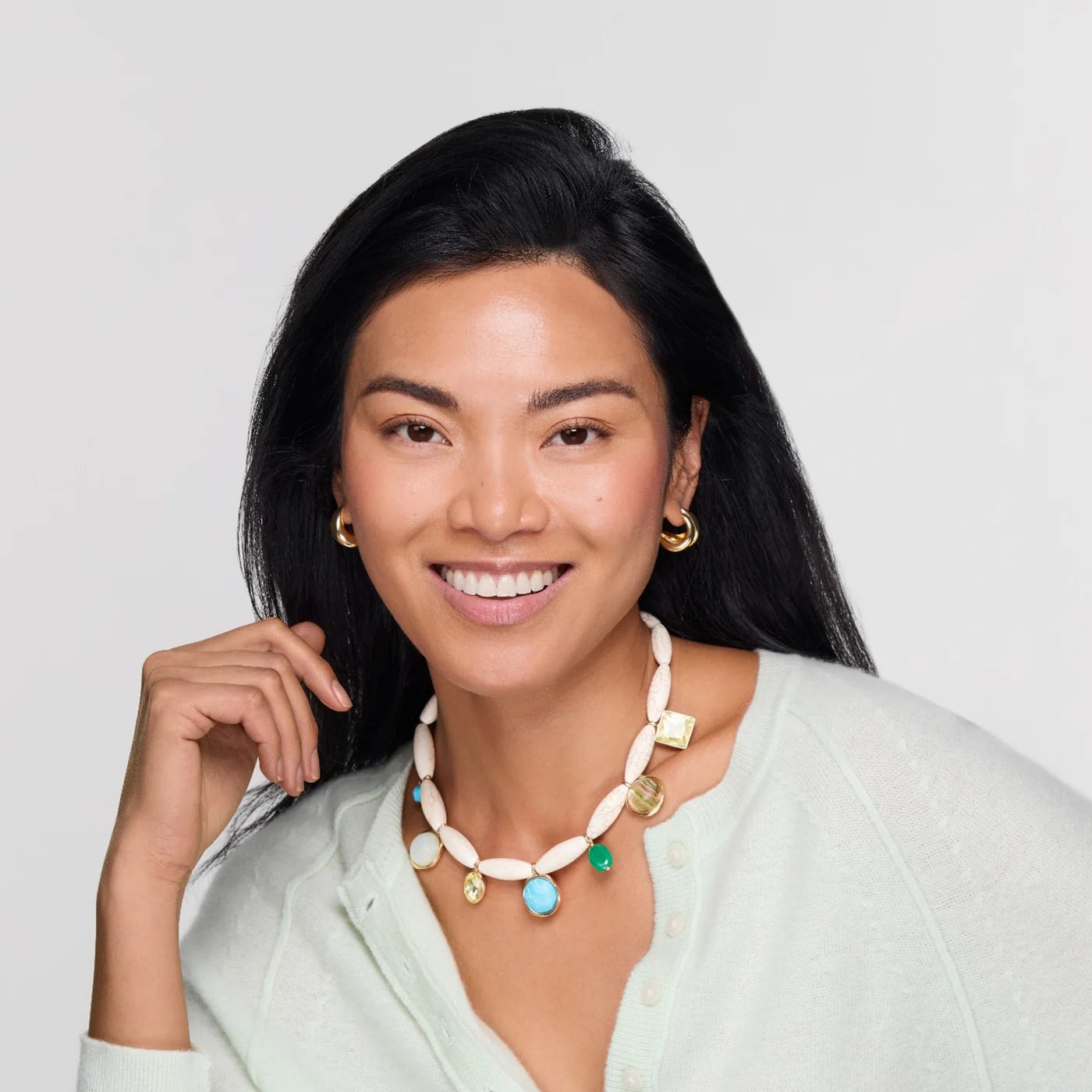 Woman wearing a colorful necklace with a plain background