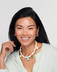 Woman wearing a colorful necklace with a plain background