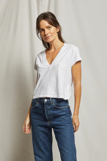 Woman wearing a white t-shirt and blue jeans against a plain background, size S