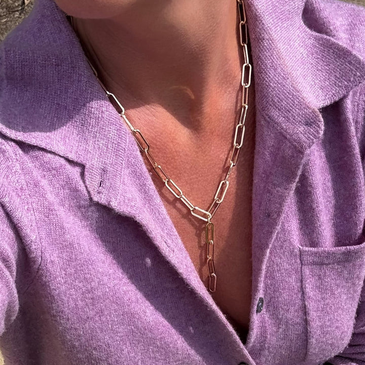 Person wearing a gold chain necklace with a purple shirt.