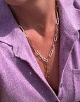 Person wearing a gold chain necklace with a purple shirt.