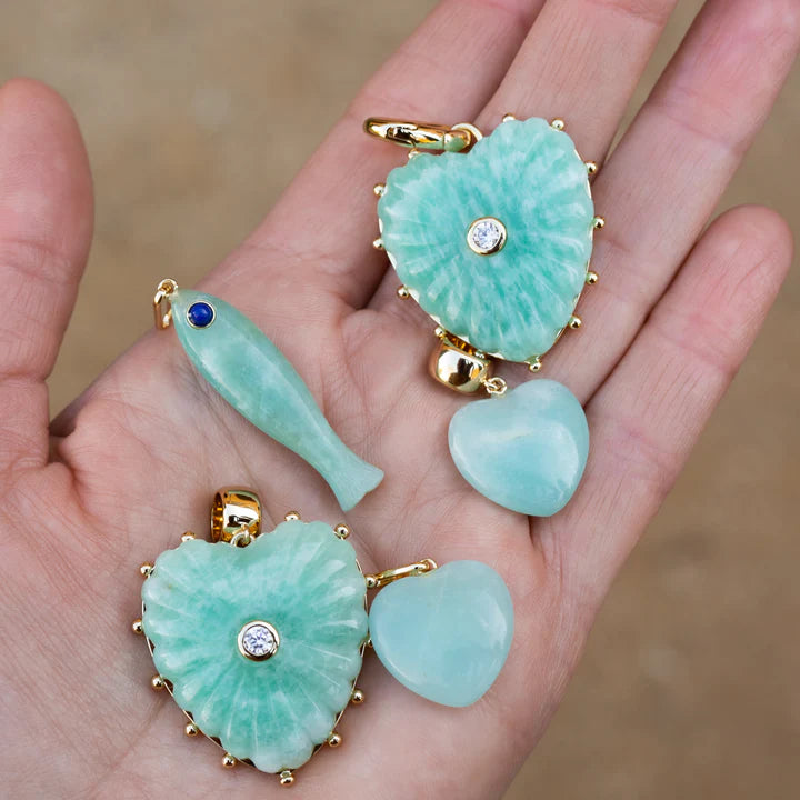 Amazonite pendants with gold accents on a hand against a blurred background