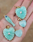Amazonite pendants with gold accents on a hand against a blurred background