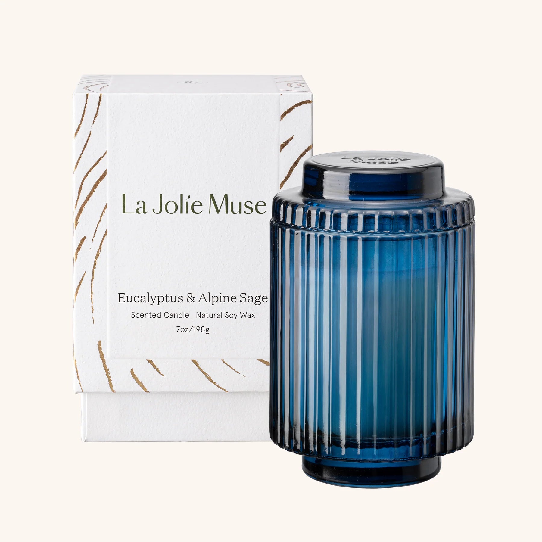 Blue candle with ribbed design and 'La Jolie Muse' packaging on a white background