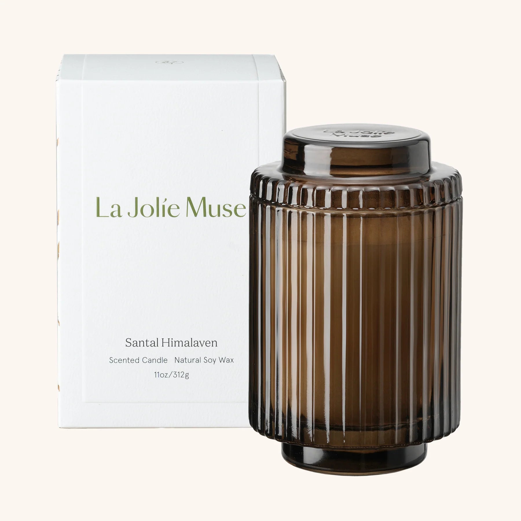 Brown candle with ribbed texture next to a white box labeled 'La Jolie Muse' on a white background