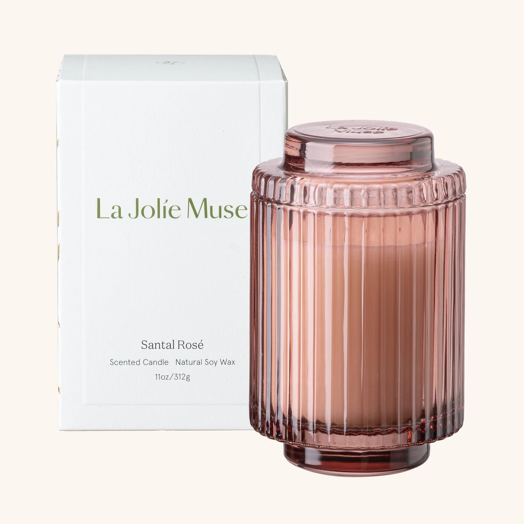 Pink scented candle with ribbed design and matching lid, next to its packaging box labeled 'La Jolie Muse'.