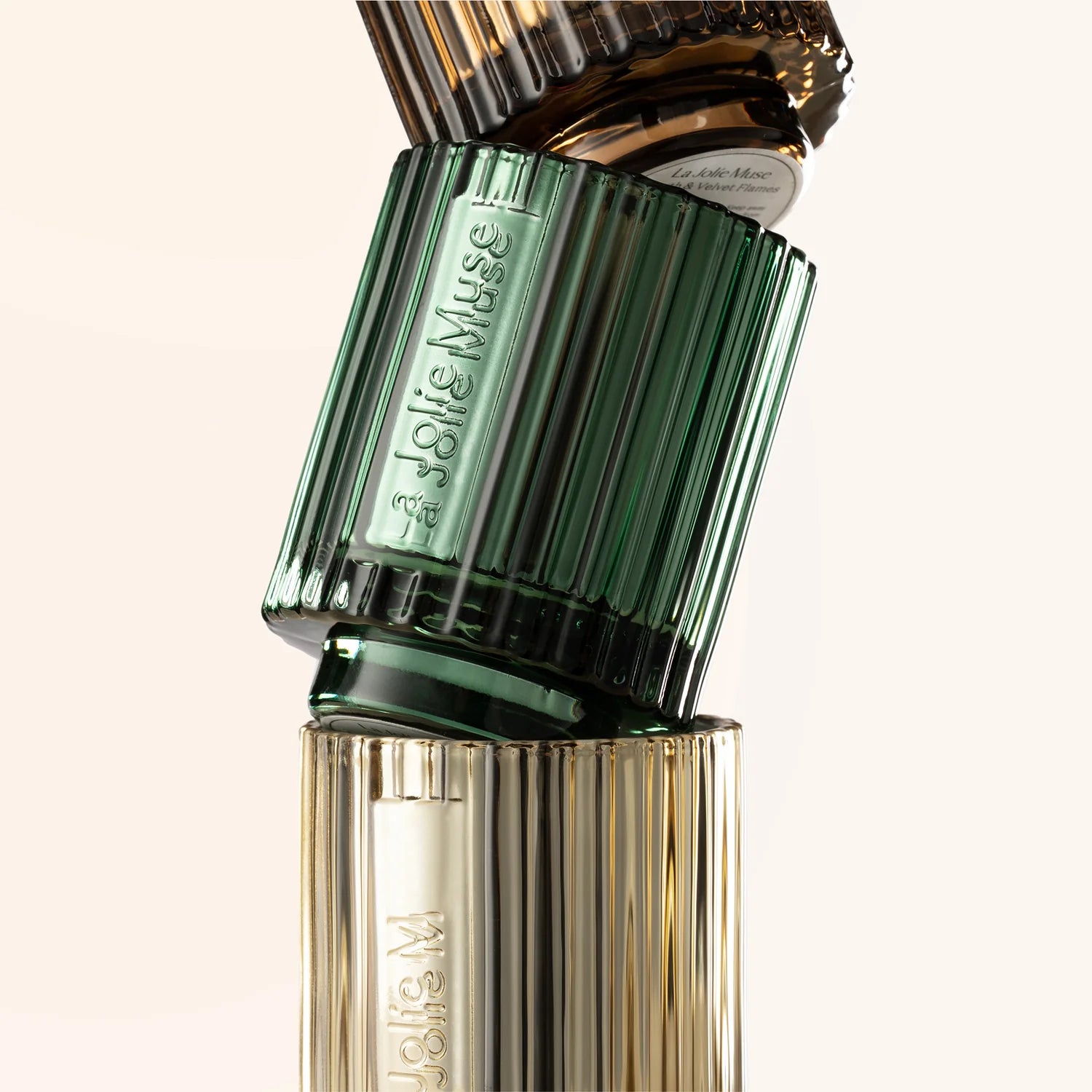 Perfume bottle with green cap and gold body on a beige background