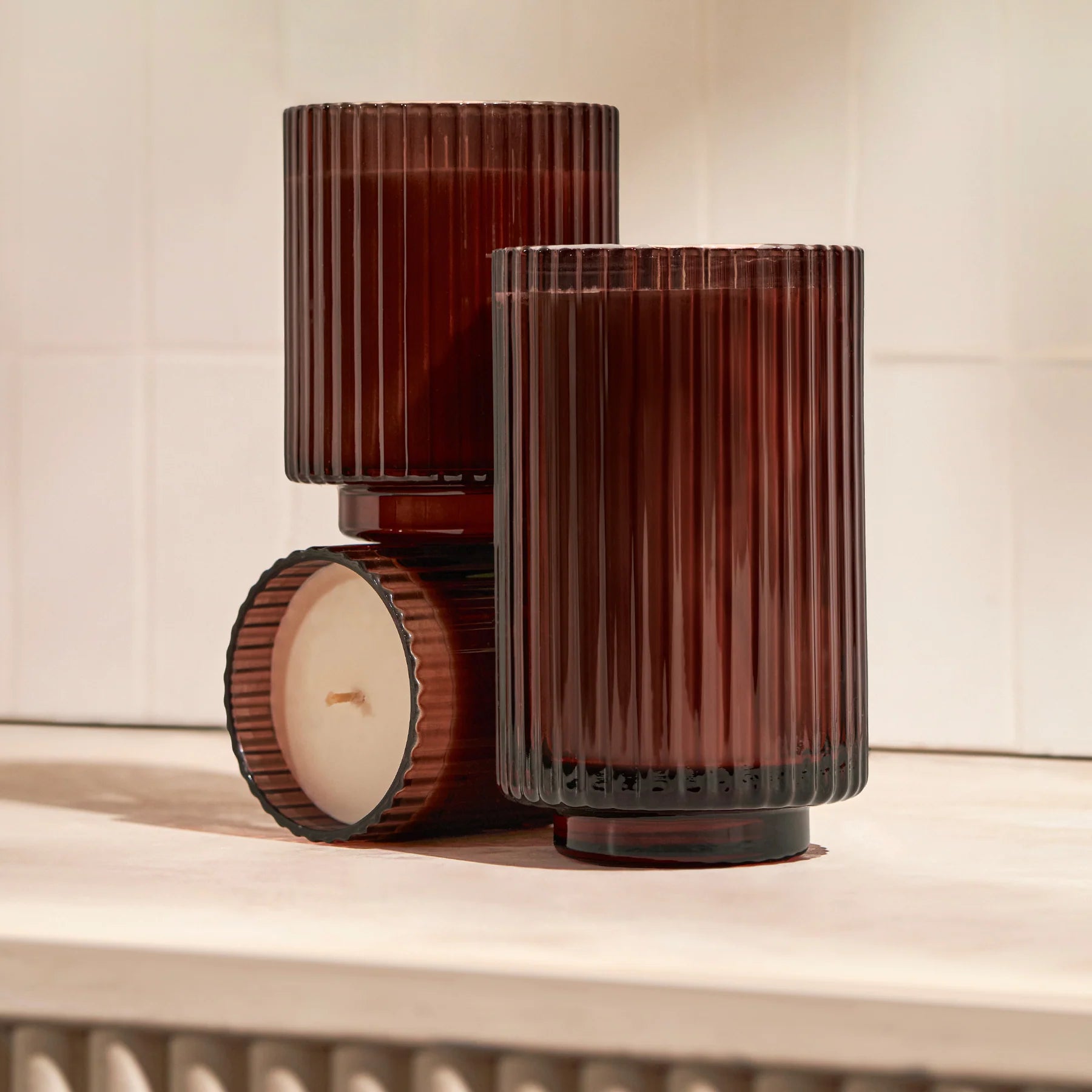 Three brown ribbed glass candles on a wooden surface.