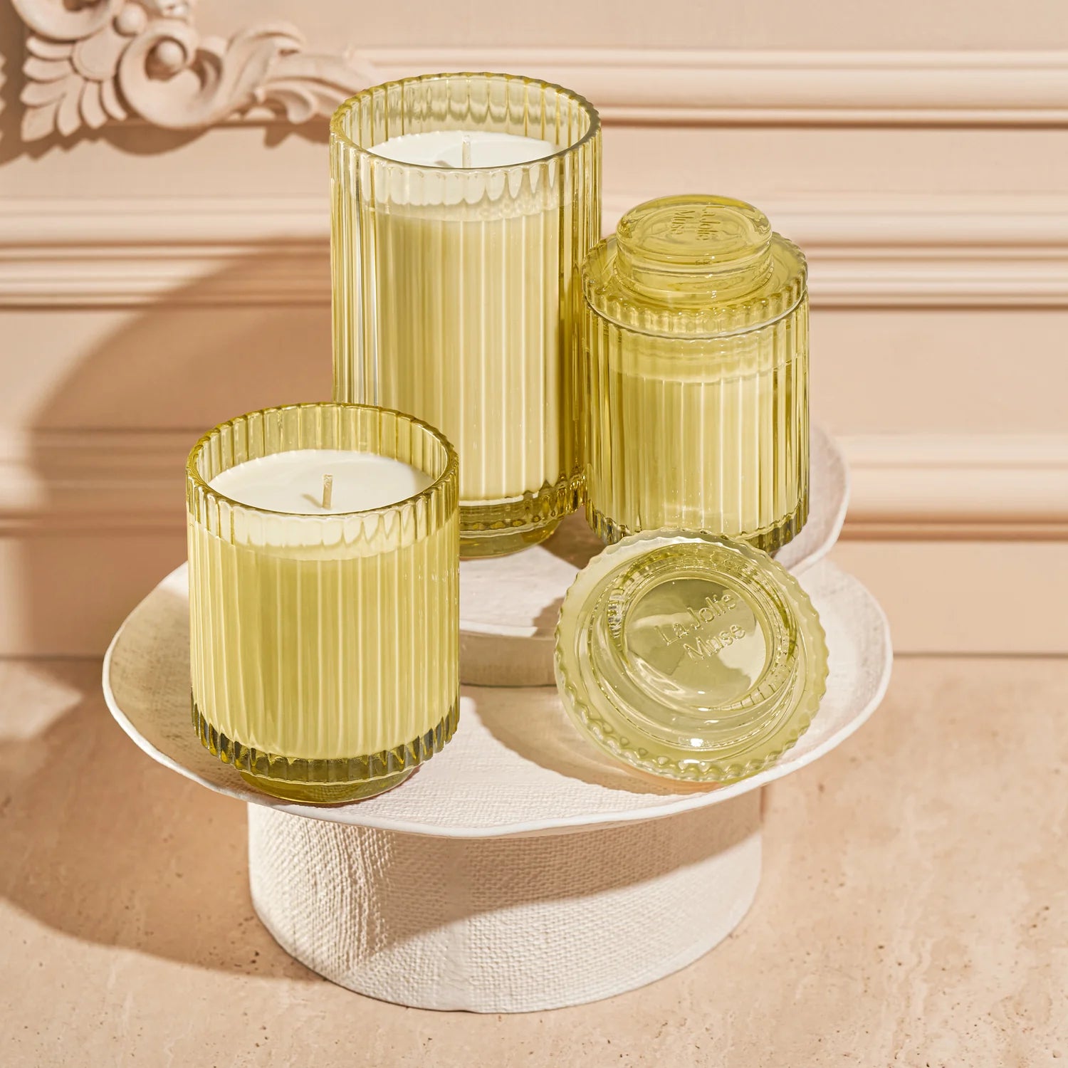 Set of yellow glass candles on a decorative stand with a beige background