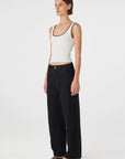 Woman wearing a white tank top and black pants on a white background