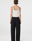 Person wearing a white tank top and black pants on a white background