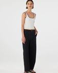 Woman wearing a white tank top and black pants on a white background