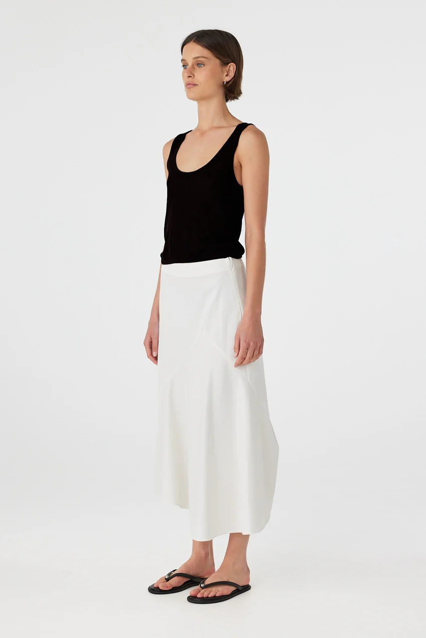 Woman wearing a black tank top and white pants on a white background