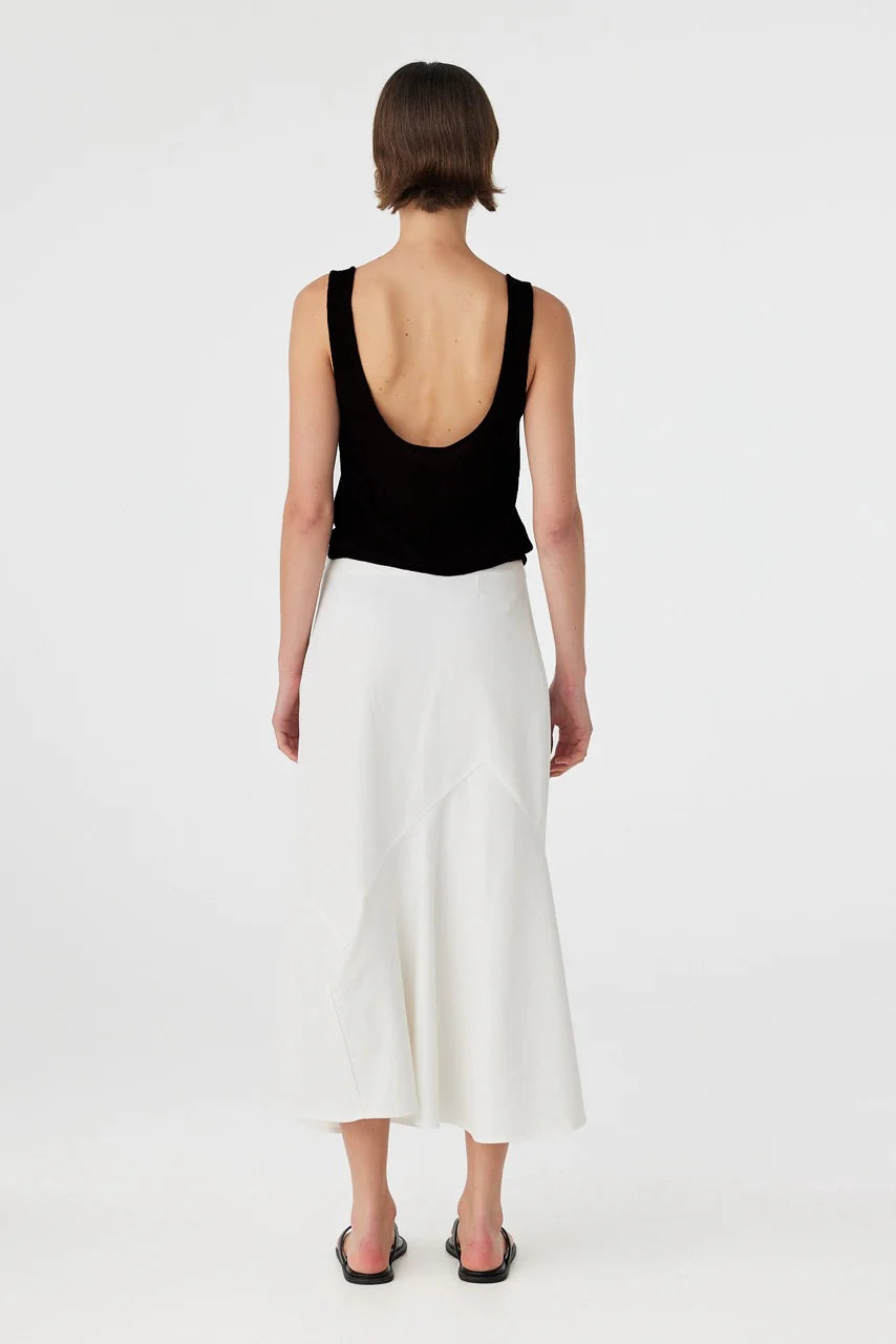 Person wearing a black sleeveless top and white skirt on a white background