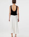 Person wearing a black sleeveless top and white skirt on a white background