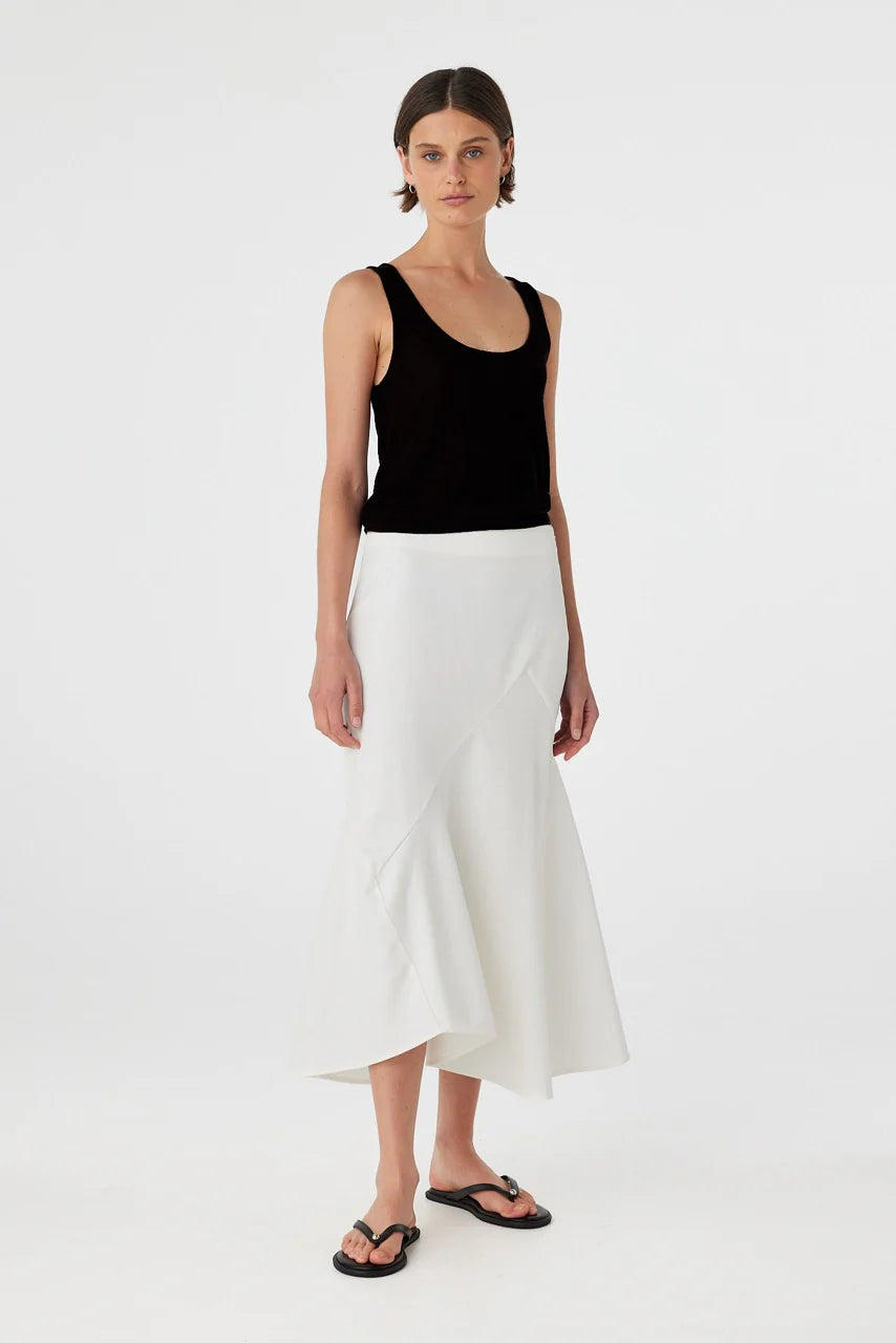Woman wearing a black tank top and white skirt on a white background