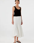 Woman wearing a black tank top and white skirt on a white background