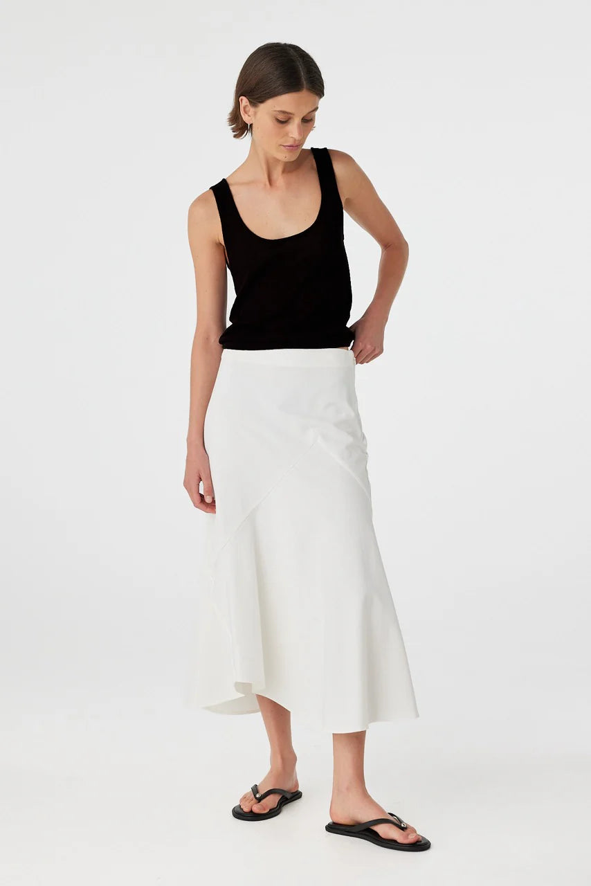 Woman wearing a black tank top and white skirt on a white background