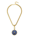 A gold-toned snake chain necklace featuring a circular pendant with a deep blue lapis lazuli-style center and a small gold star motif, displayed on a clean white background.