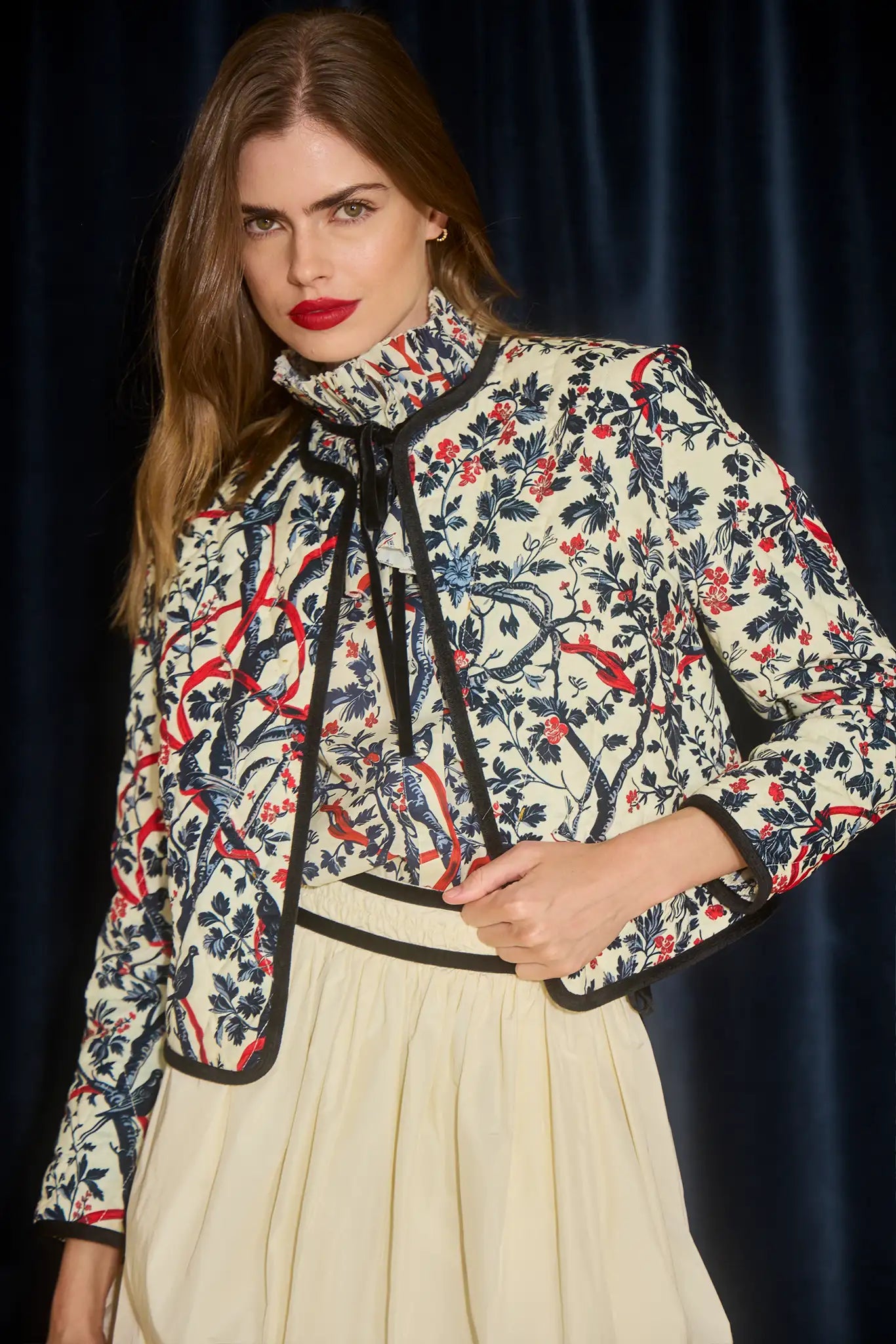 Woman wearing a floral patterned jacket and Angelina Skirt with a dark background
