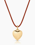 Gold heart-shaped pendant on a red cord against a white background