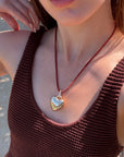 Woman wearing a brown textured top and a necklace with a heart pendant.