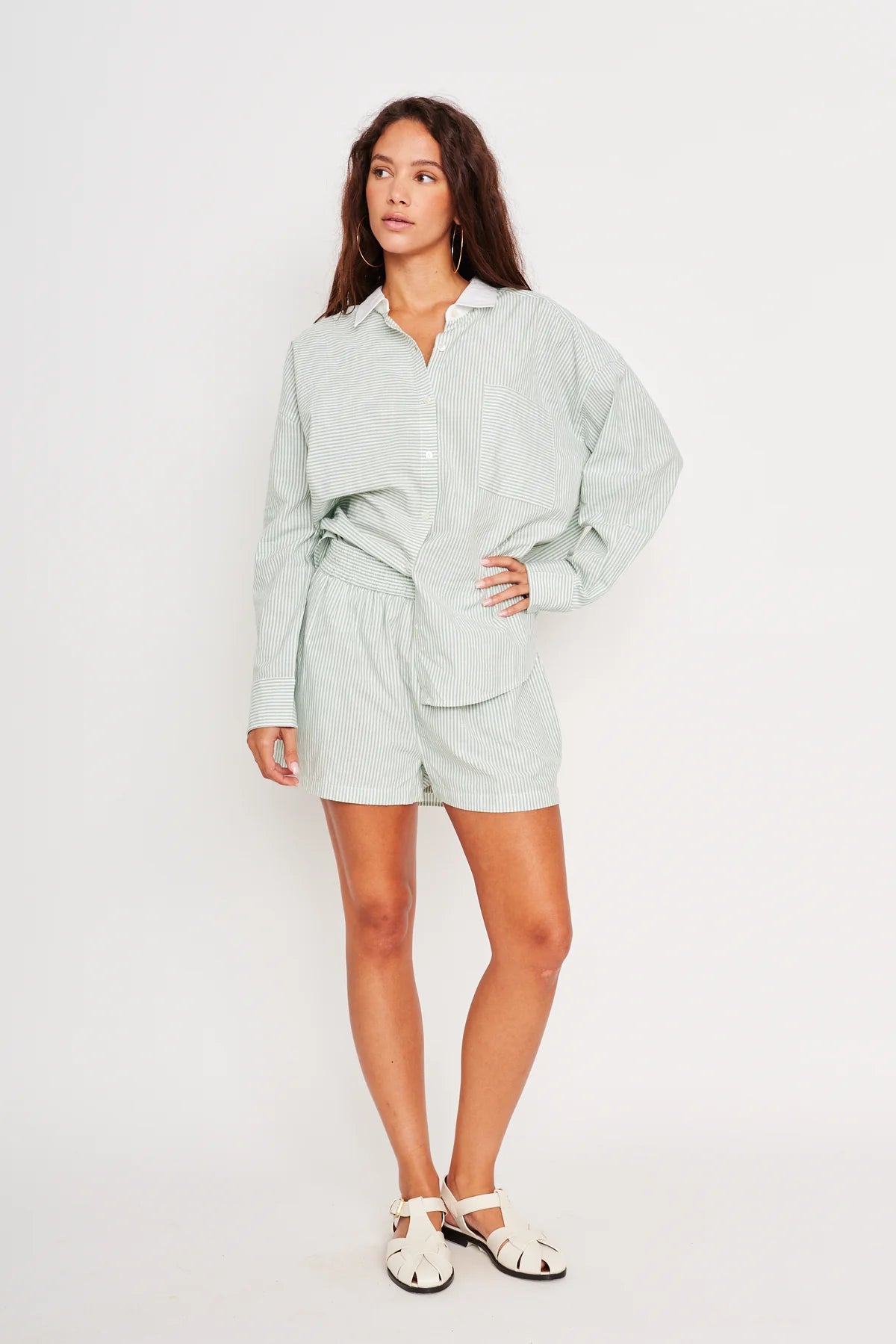 Woman wearing a light green shirt and shorts set on a white background