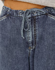 Close-up of blue denim pants with a drawstring waistband.