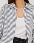 Person wearing a striped shirt over a white top with a neutral background
