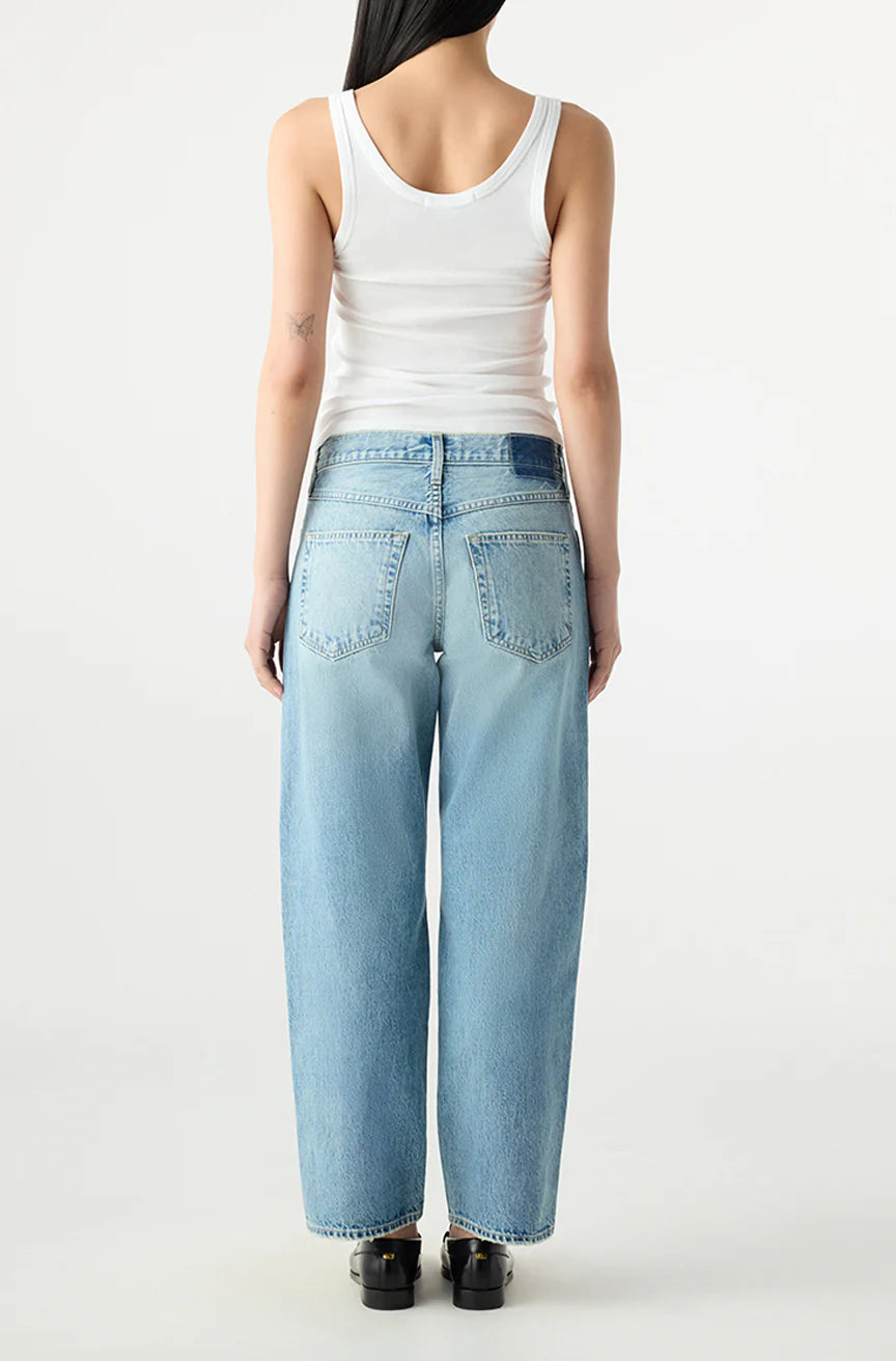 Person wearing a white tank top and light blue jeans on a white background, back