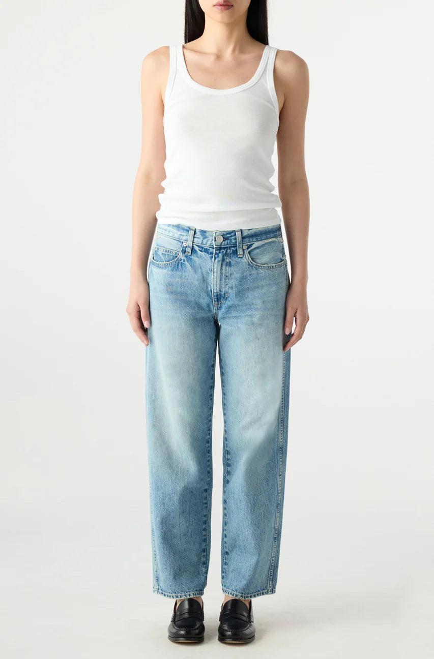 Person wearing a white tank top and light blue jeans on a white background