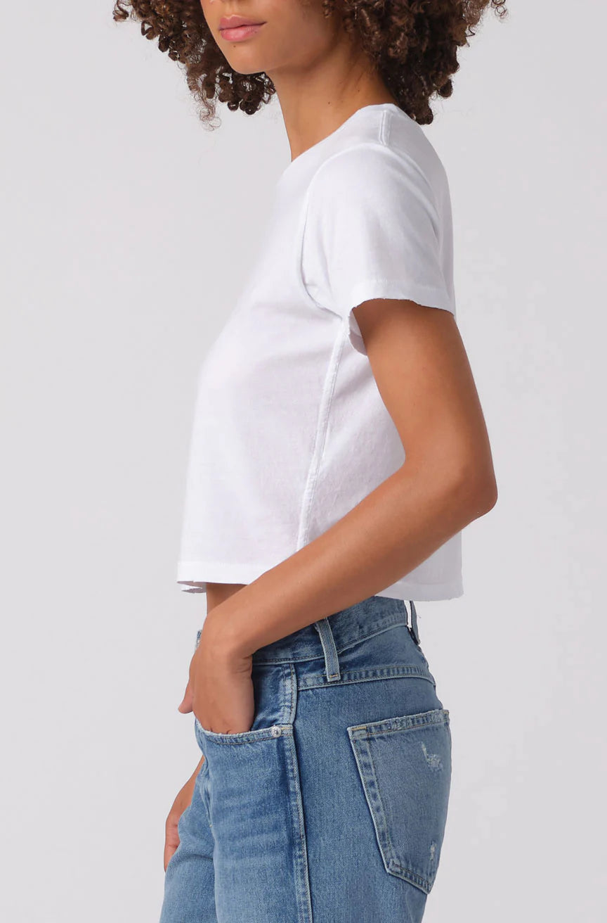 Person wearing a white t-shirt and blue jeans on a plain background