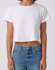 Person wearing a white crop top and blue jeans on a plain background
