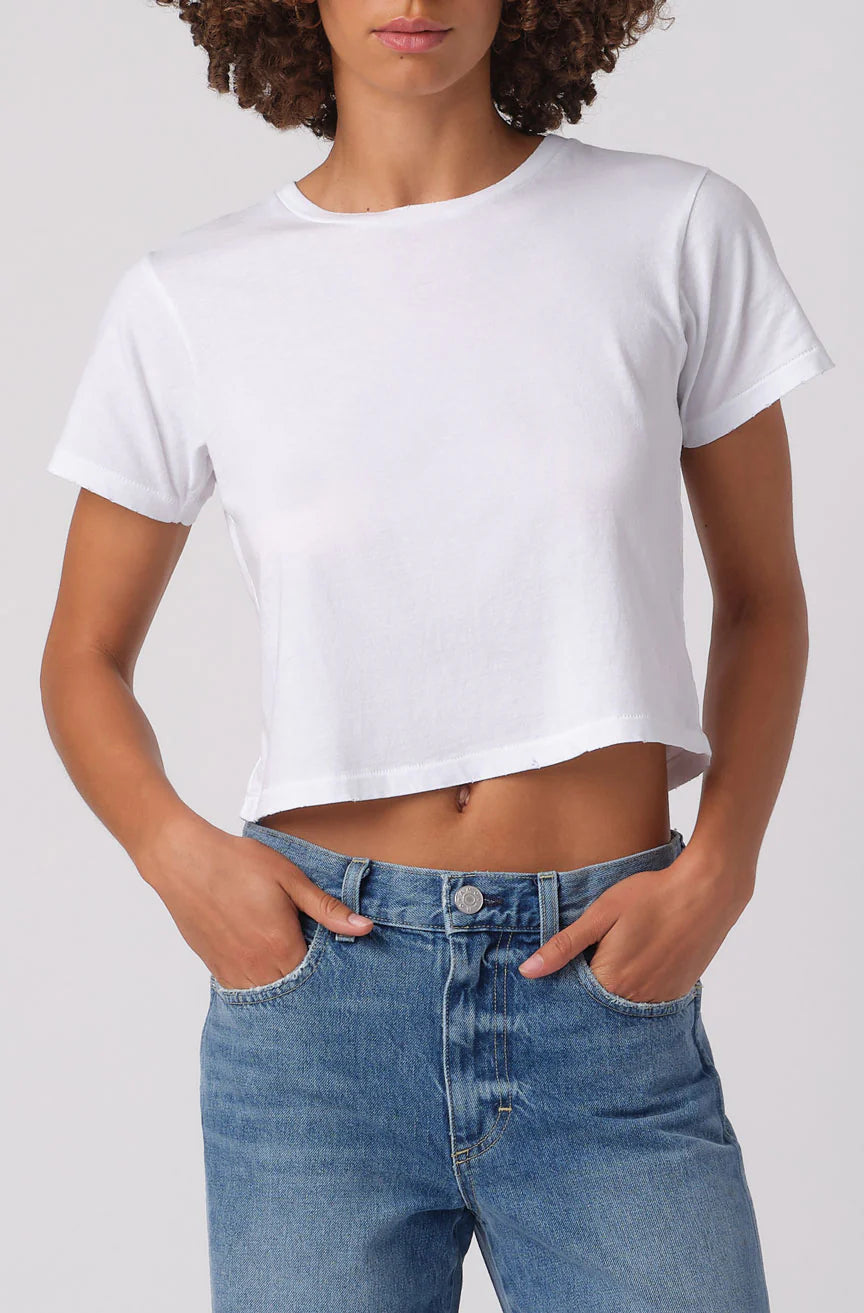 Person wearing a white crop top and blue jeans on a plain background