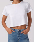 Person wearing a white crop top and blue jeans on a plain background