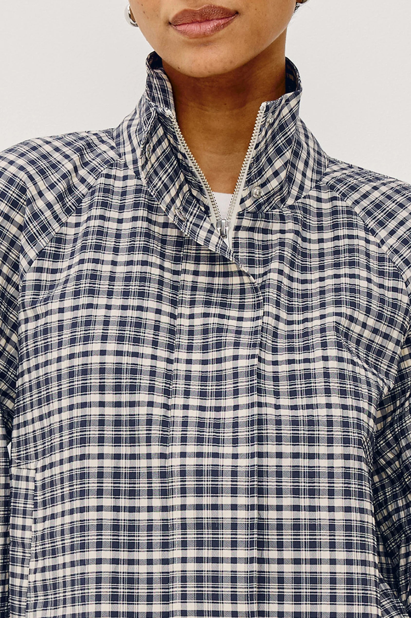 Person wearing a blue and white checkered shirt with a close-up on the collar.