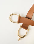Brown leather belt with gold hardware on a white background