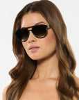 Woman wearing green tortoise sunglasses with a plain background
