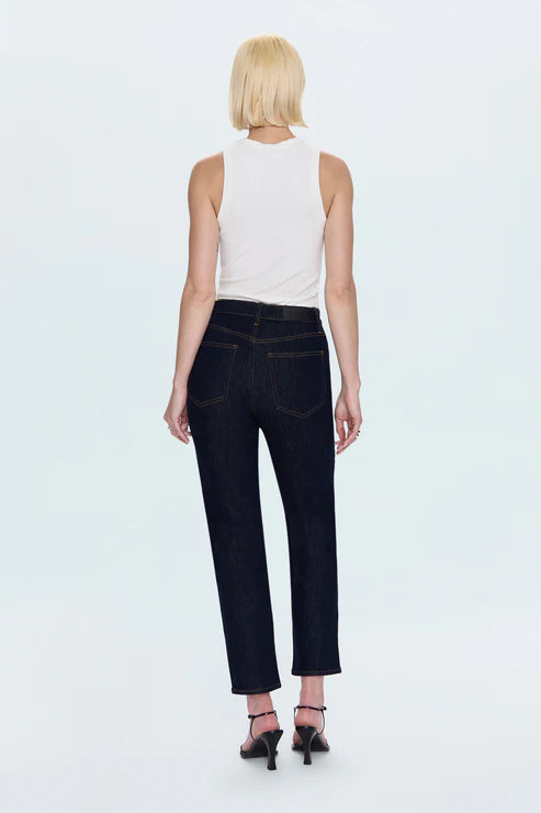 Woman wearing a white sleeveless top and dark jeans on a light gray background back view