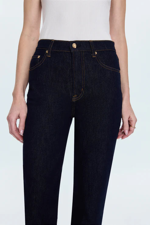 Dark blue jeans worn by a person on a white background detail view