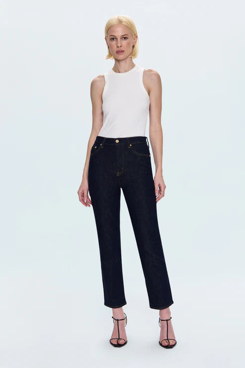 Woman wearing a white sleeveless top and black jeans on a light blue background
