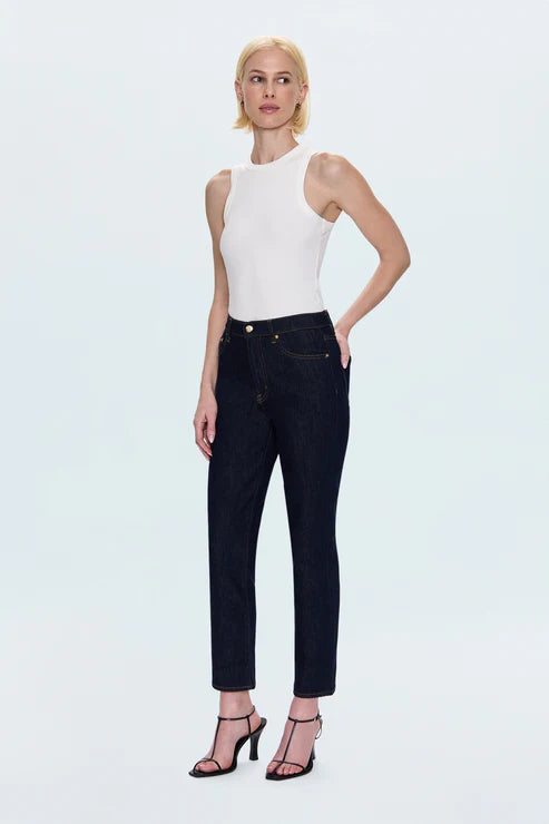 Woman wearing a white sleeveless top and black jeans on a light gray background