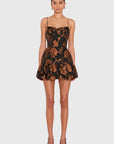 A model wearing a black spaghetti-strap mini dress with a brown floral jacquard pattern, paired with black high heels, against a light gray background.