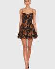 A model wearing a black and brown floral lace mini dress with spaghetti straps and a ruffled hem, paired with black pointed-toe heels, against a light gray studio background.