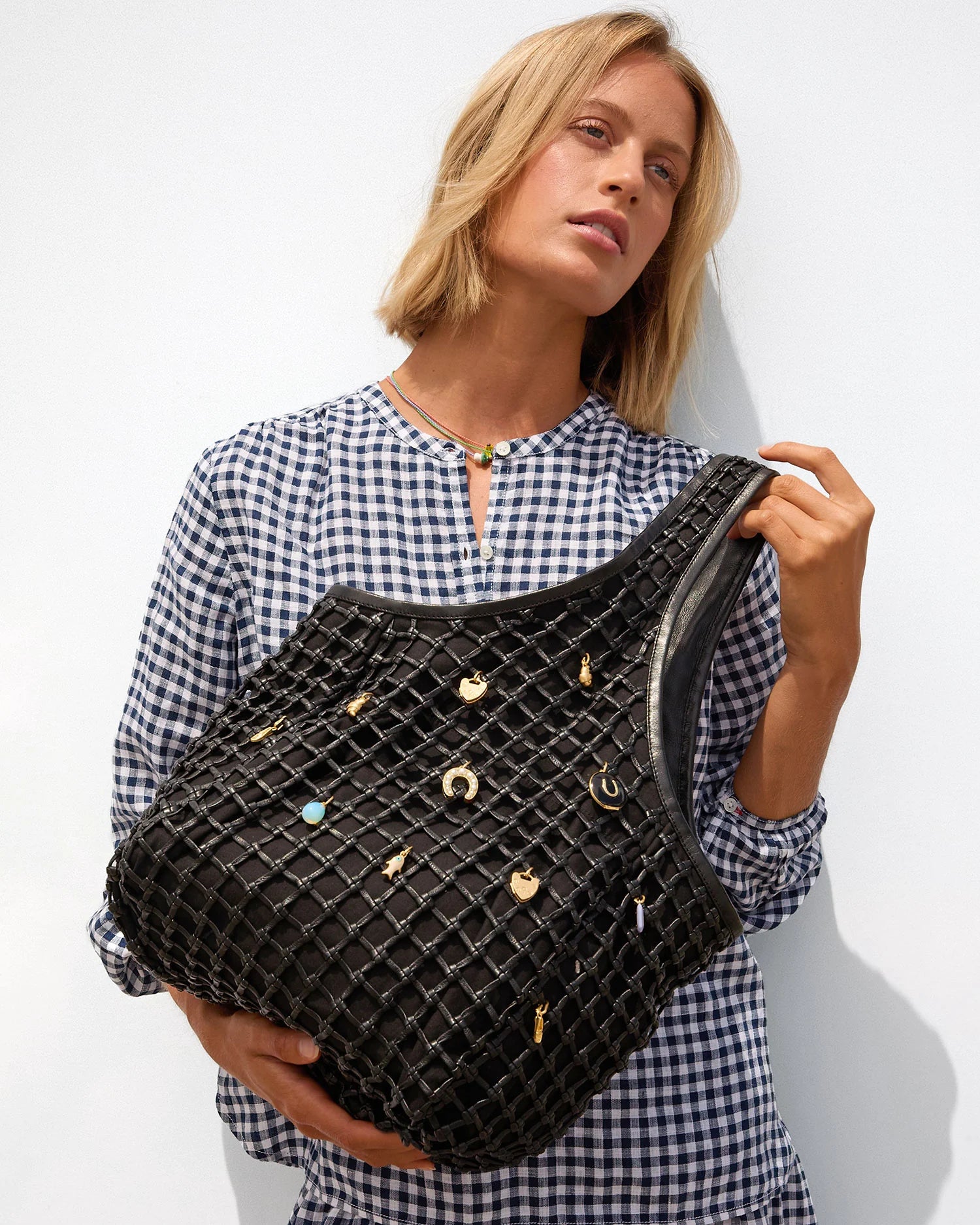 Woman holding a black textured handbag with decorative elements against a white background
