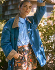model wearing floral shorts, blue button up top and denim jacket