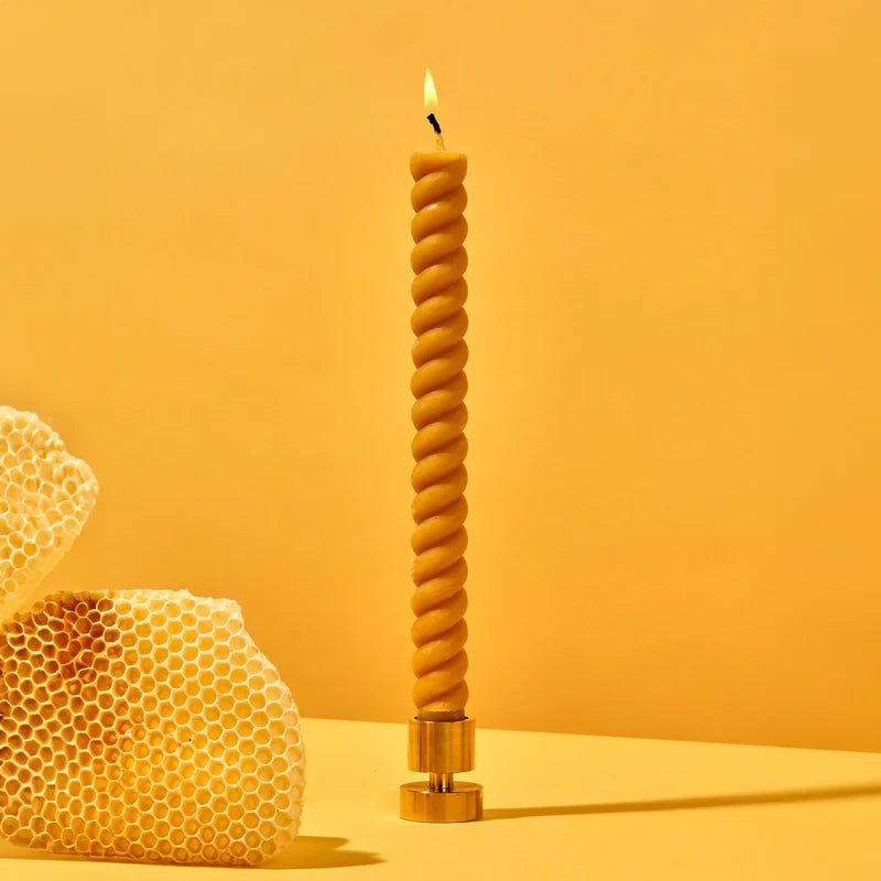 Twisted candle with honeycomb on a yellow background